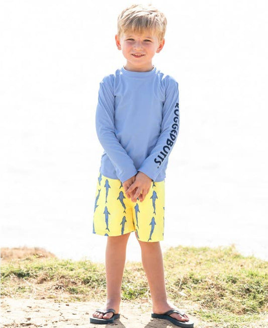 boy wearing blue swim top as well as shark designed swim bottoms 